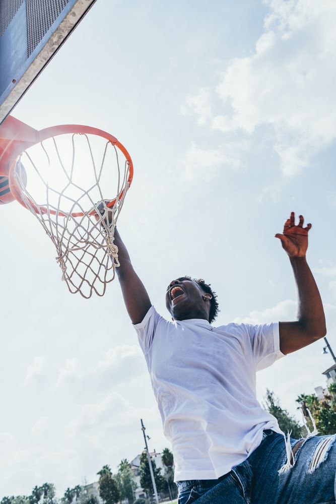 Black sportsman hanging on basketball lap