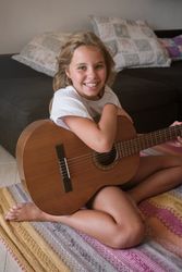 Girl with guitar smiling and looking at camera