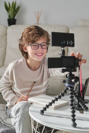 Positive boy making video for blog using professional equipment