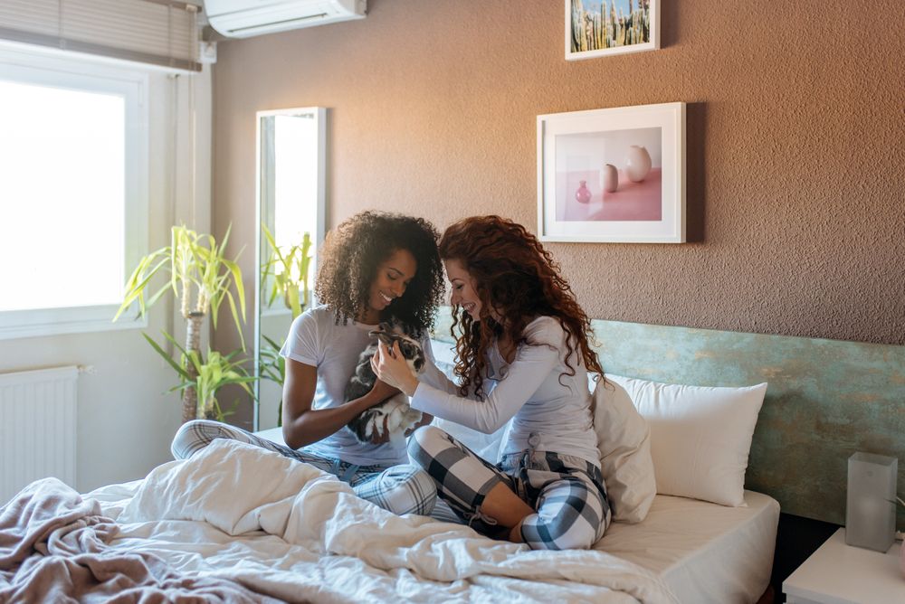 Young women in bed playing with little bunny
