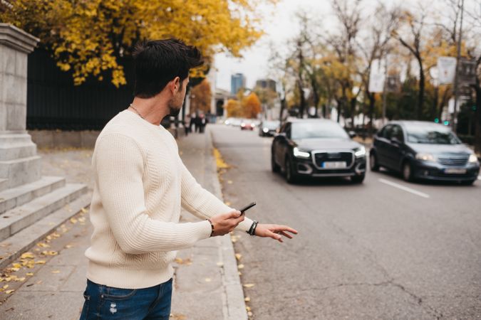 Young male hitchhiking with smartphone