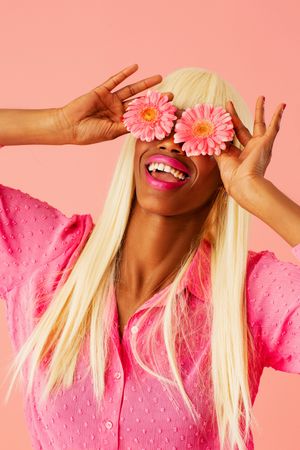 Black woman in blonde wig with pink flowers over her eyes