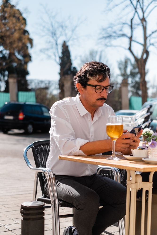 Smart mature entrepreneur using smartphone at cafe veranda