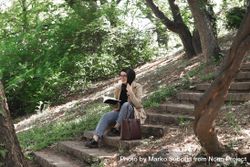 Smiling woman on outdoor staircase holding book 5QWYdb