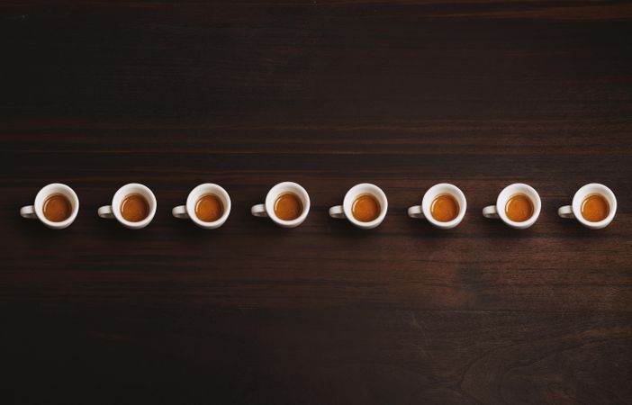 Row of espresso shots on a wooden table