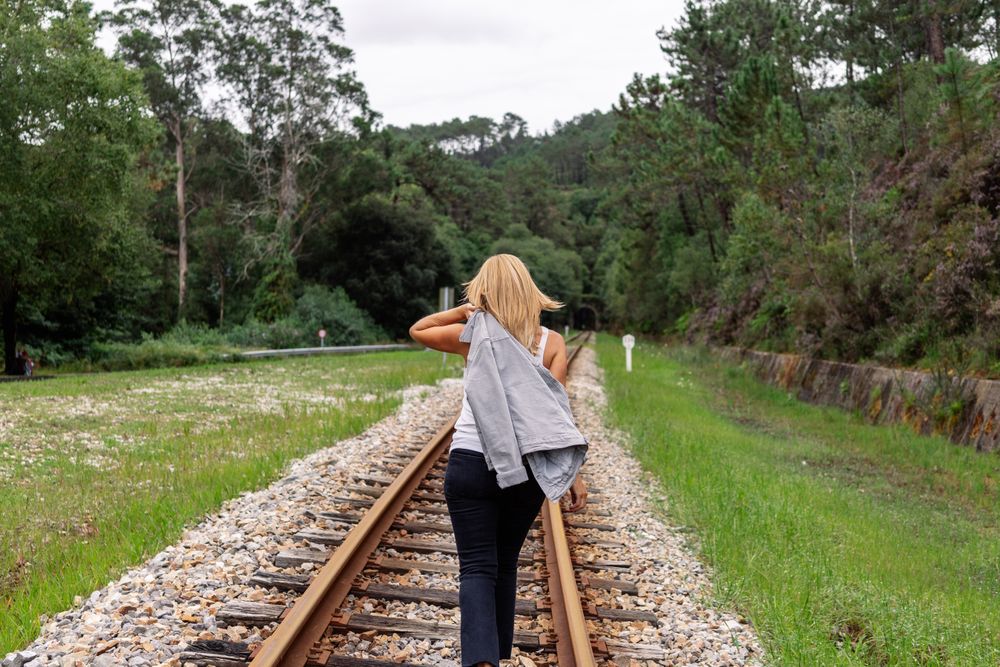 Woman walking along railway though greenery part of road