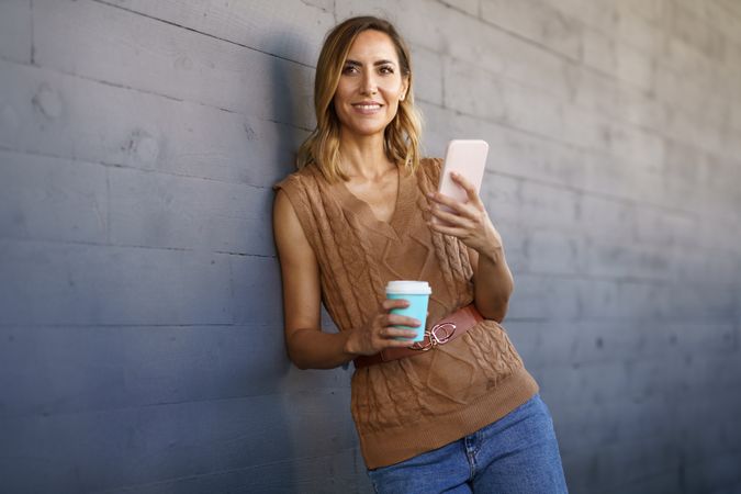 Stylish female with coffee browsing cellphone