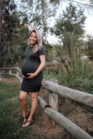Happy pregnant woman standing at river in park