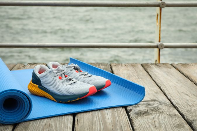 Karemat and sneakers on wooden floor outdoors, space for text