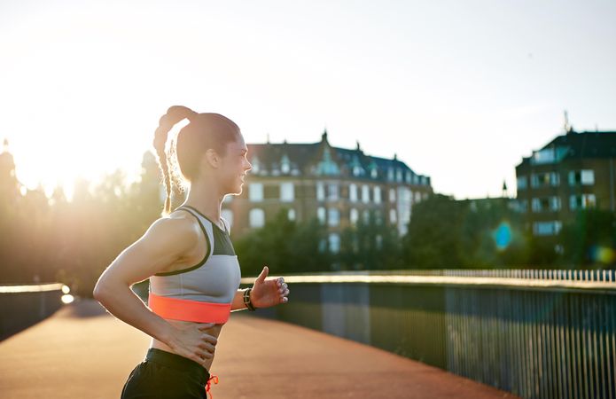 Side view of fit woman working out on bridge