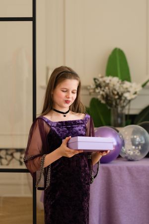 Girl looking at gift box at birthday party.