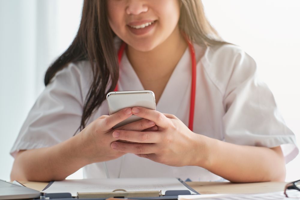 Anonymous doctor browsing smartphone at table