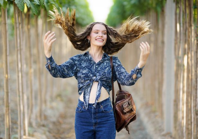 A Joyful Young Woman with Flowing Hair Strolling Along a Picturesque Path in a Vineyard
