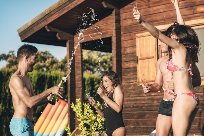 Guy pouring champagne over his friends