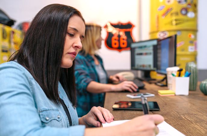 Portrait of brunette woman with long hair checking orders received by ecommerce shop