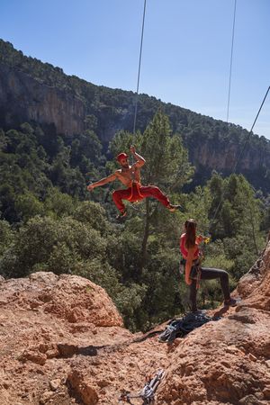 Couple descending from rocky cliff