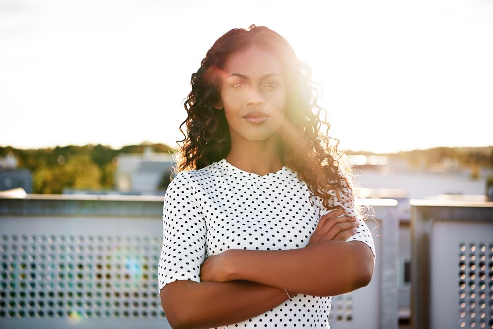 Woman with arms crossed standing on sunny roof