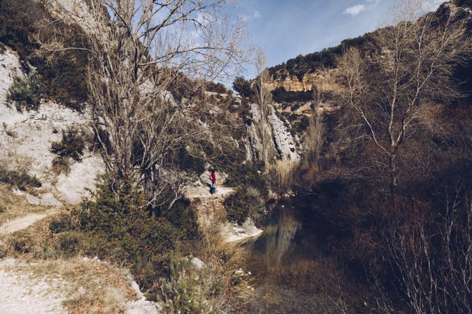Traveling woman on lake in rocky cliffs