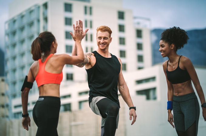 Female athlete giving high five to a man after fitness training standing on rooftop