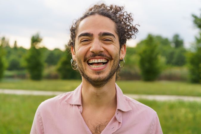 Joyful man with curly hair laughing in park