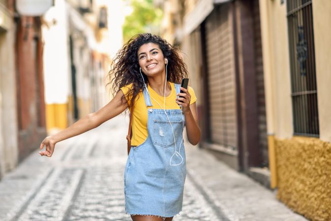 Arab woman listening to music with earphones and dancing outdoors