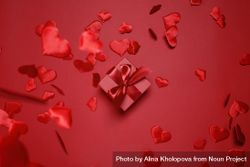 Red box with red bow on red background surrounded by falling red hearts 5arkv4