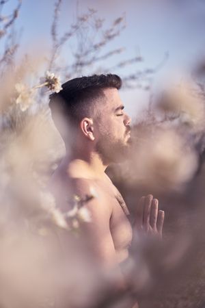 Shirtless man meditating in spring garden