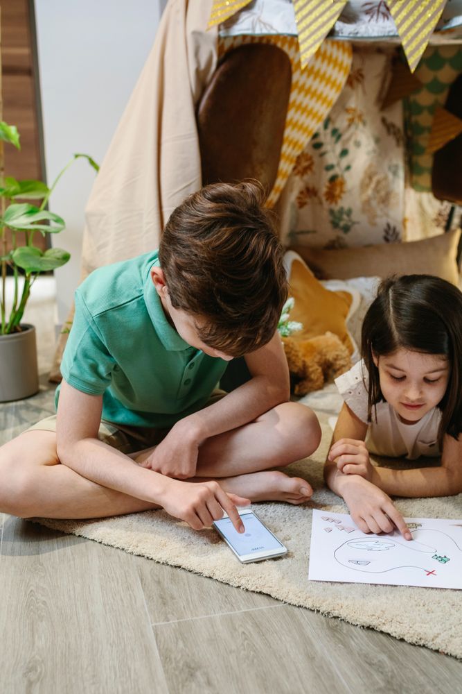 Boy and girl playing treasure hunting game in a tent at home