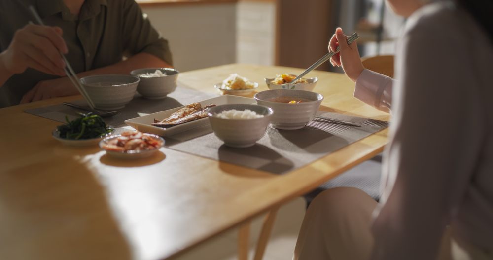 Couple Eating Delicious Korean Dinner with Chopsticks in the Kitchen at Home.