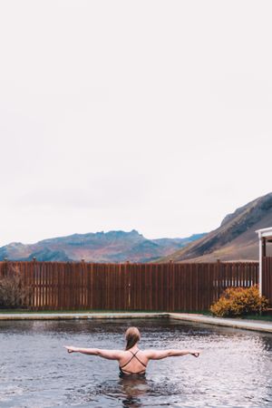 Woman in pool near sea and hills on shore