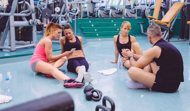 Group of friends sitting in the middle of gym and talking