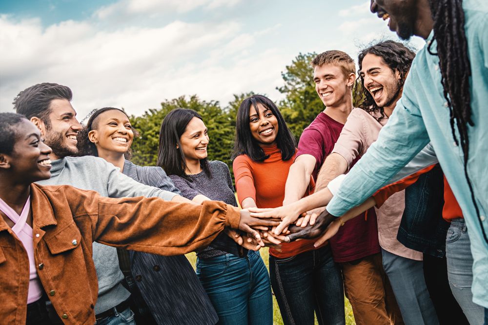 Inclusive team joining hands together outside