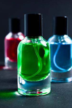 Green, blue and red glass bottles in dark studio