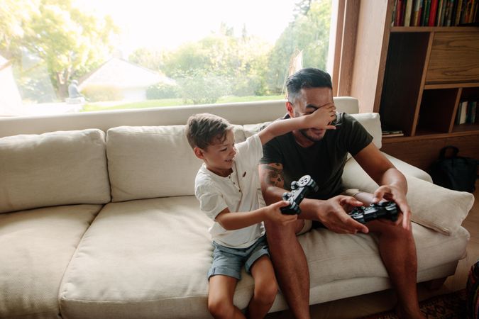 Cheerful family of father and son having fun playing video games at home