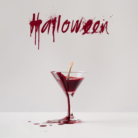 Doll hand drowning in martini glass full of blood with “Halloween” text