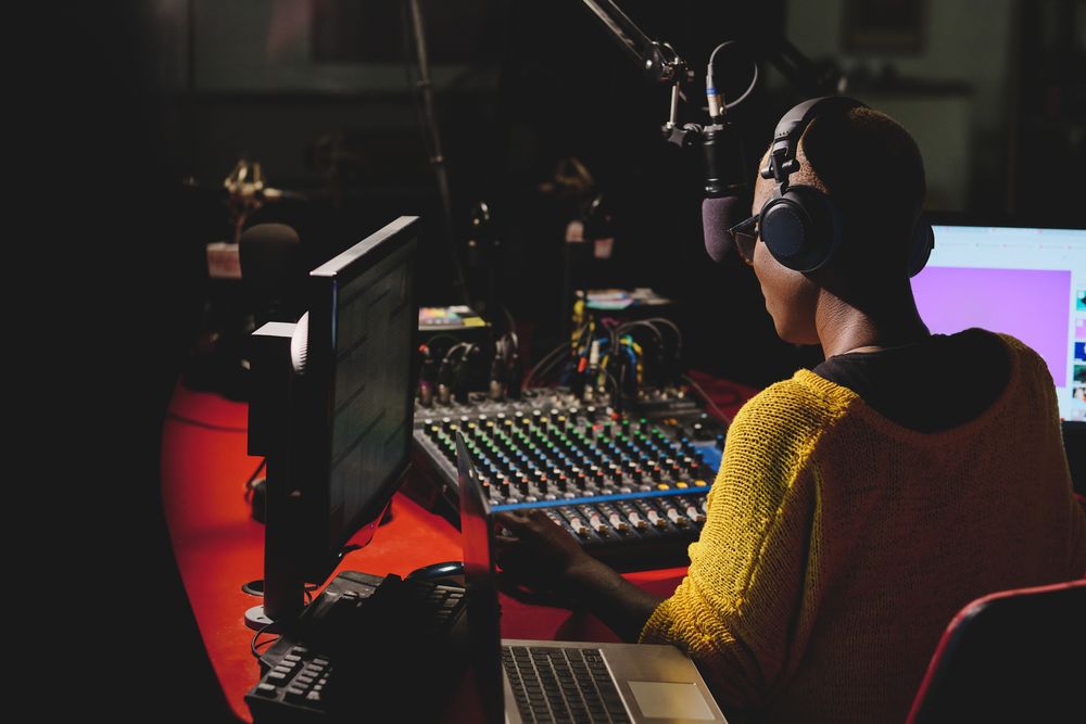 Black radio host in headphones working in dark studio