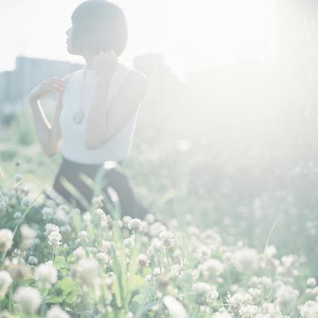 Woman standing in light flower field looking away