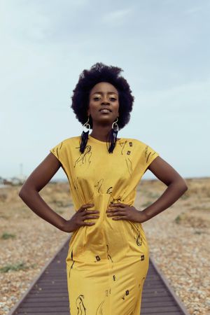 Black woman in yellow dress standing in desert