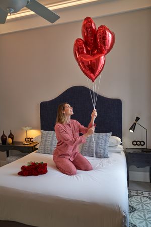 Woman with red heart balloons and bouquet of roses