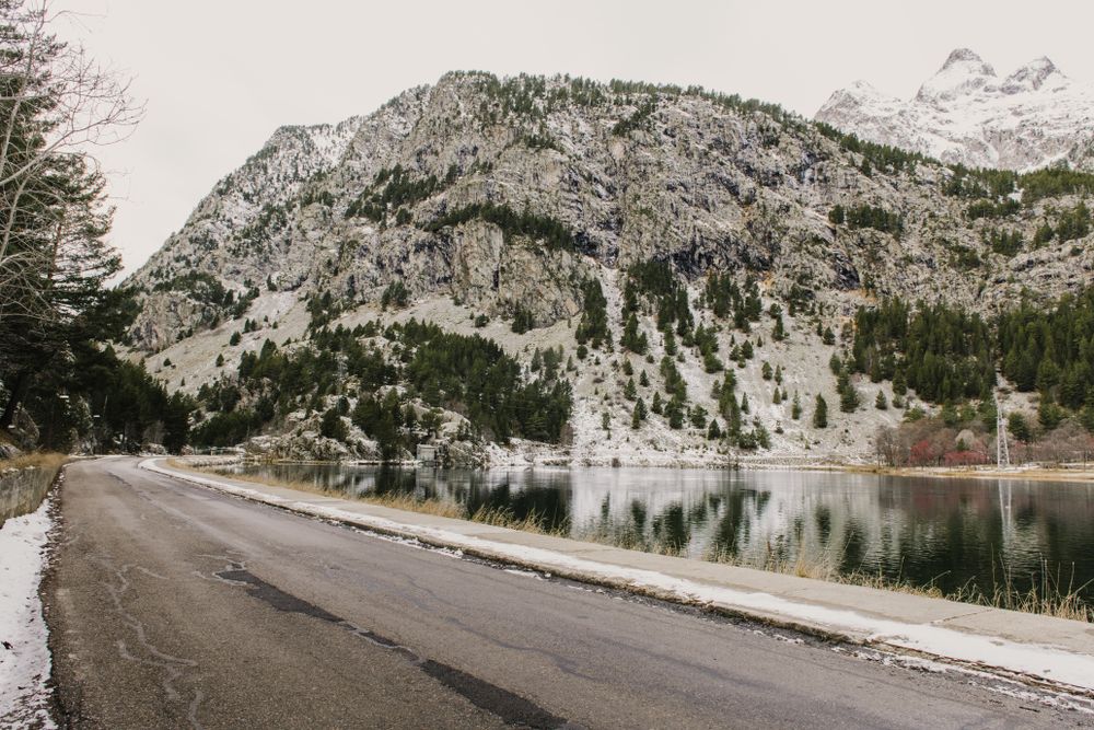 Countryside road between snow hills and lake