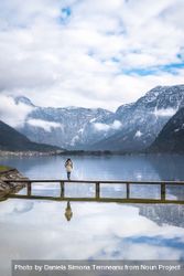 Peaceful woman enjoying an alpine scenery on a bridge over alpine lake 5QYld5