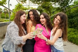 young women friends toasting with a mojito and smiling with joy