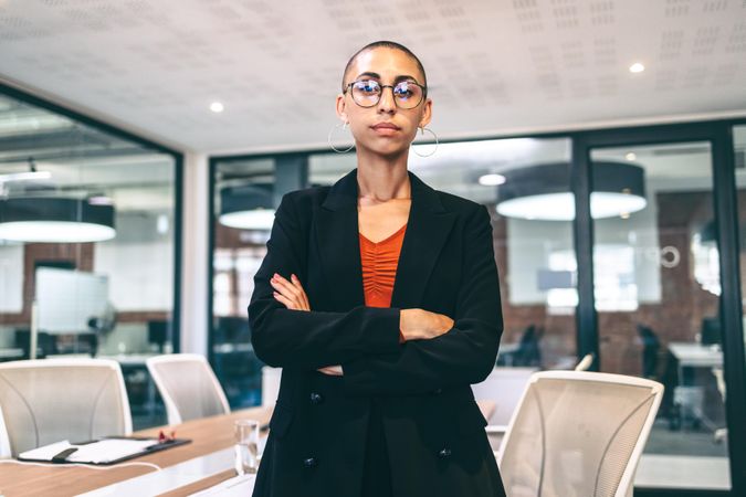 Young businesswoman looking serious while standing with her arms crossed in a boardroom