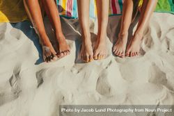 Group of female legs in sand with colorful pedicures 4B6O34
