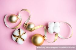 Gold Christmas baubles and cotton on pink background 5oGAx5
