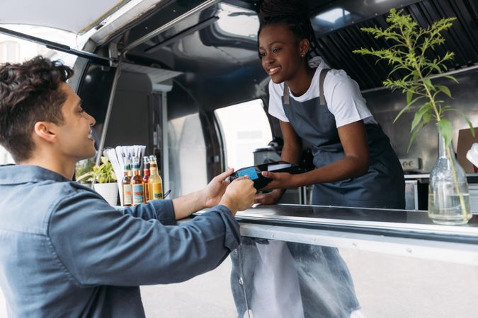 Male paying food truck vendor using credit card terminal