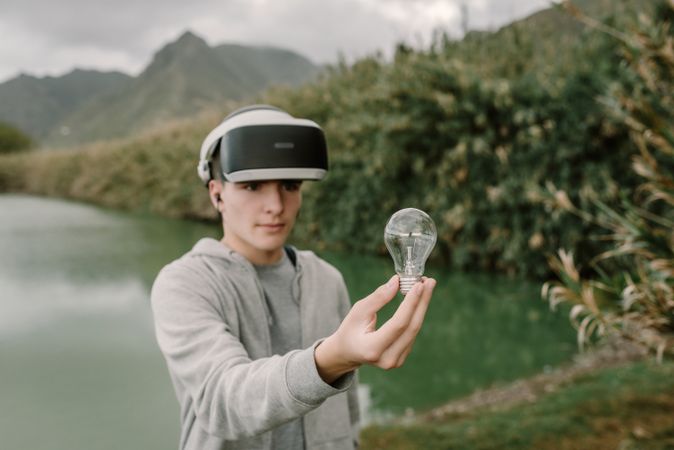 Young teenager with virtual reality glasses holding a light bulb
