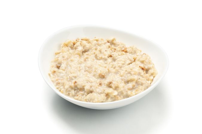 Plate with cooked oatmeal isolated on plain background