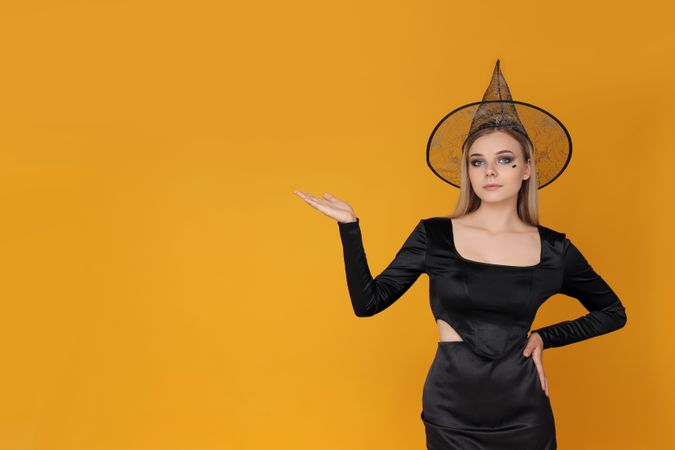 Concept of Halloween, young woman on yellow background