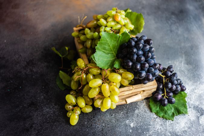 Box of fresh green & red grapes on dark grey kitchen counter